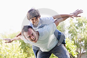 Man and young boy outdoors playing airplane