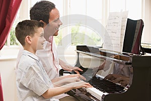 Man and young boy playing piano and smiling