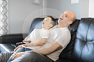 Man and young boy with remote control yawn