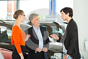 Man with young couple in car dealership