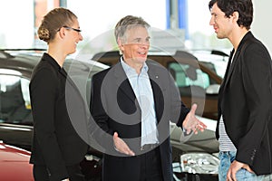 Man with young couple in car dealership