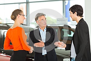 Man with young couple in car dealership