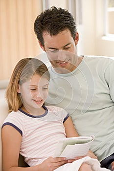 Man and young girl in living room reading book