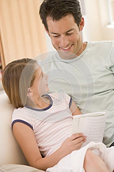 Man and young girl in living room reading book