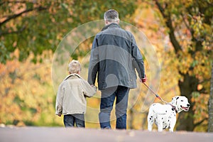 Man With Young Son Walking Dog Through Park