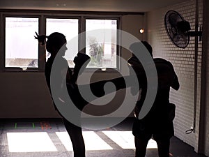 Man and young woman fighting together. Female practicing boxing. Fit woman and her trainer boxing indoors. Portrait of young