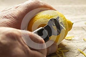 Man zesting a lemon with a lemon zester on a chopping board