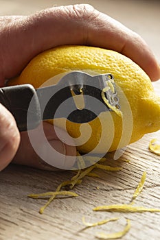 Man zesting a lemon with a lemon zester on a chopping board