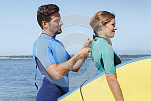 Man zipping up girlfriends wetsuit photo