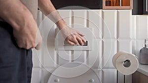 The man zips up his fly and flushes the toilet by pressing the half-flush button