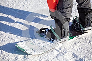 A man zips up a snowboard with boots on the snow.