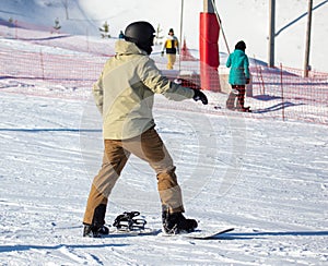 A man zips up a snowboard with boots on the snow.