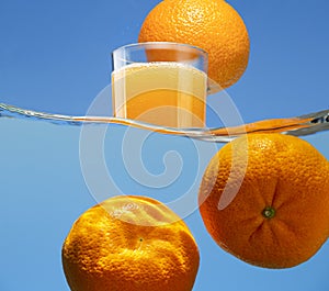 Manadrins under water against the background of a glass with an orange drink