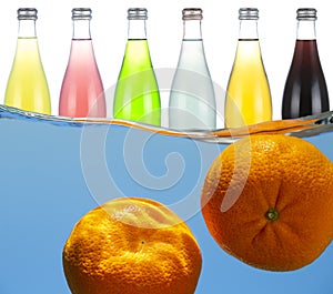 Manadrins under water on a background of glass bottles with fruit drinks