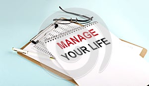 MANAGE YOUR LIFE text on notepad on clipboard with chart on blue background, concept closeup. Business and finance concept