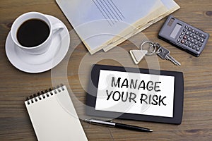 Manage Your Risk. Text on tablet device on a wooden table