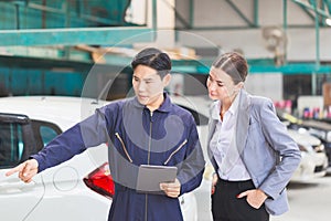 Manager and auto mechanic in auto repair shop, Mechanic and young woman client talking together at the repair garage, Car repair