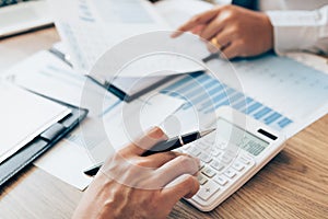 Manager calculates about the company finances by pressing on the calculator on the table with the employee explaining the summary