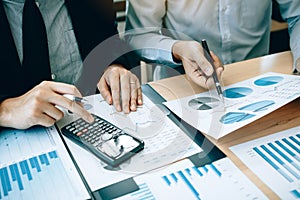 Manager calculates about the company finances by pressing on the calculator on the table with the employee explaining the summary