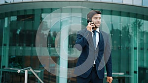 Manager calling phone while walking at city with blurred background. Exultant.