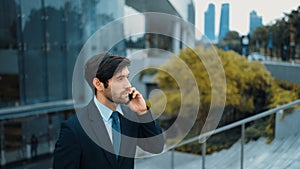 Manager calling phone while walking at city with blurred background. Exultant.