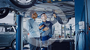 Manager Checks Data on a Tablet Computer and Explains the Breakdown to a Mechanic. Car Service Emp