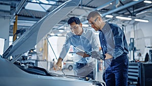 Manager Checks Diagnostics on a Tablet Computer and Explains the Engine Breakdown to a Mechanic. C