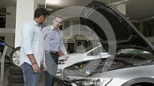 The manager demonstrates the customer a motor in modern car