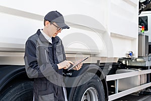 Manager with a digital tablet next to garbage truck.