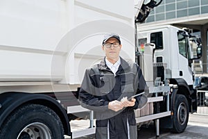 Manager with a digital tablet next to garbage truck.