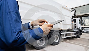 Manager with a digital tablet next to garbage truck.