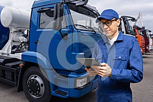 Manager with a digital tablet next to trucks.