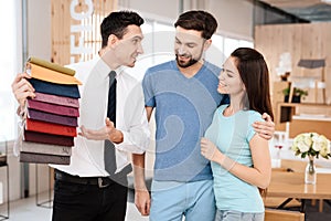 The manager of the furniture store holds samples of fabrics for furniture upholstery.