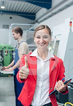 Manager giving thumbs-up sign standing on the factory floor