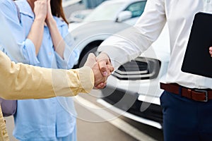 Manager greets a client at a car dealership