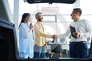 Manager greets clients at a car dealership