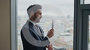 Manager holding paper airplane standing at window looking cityscape close up.