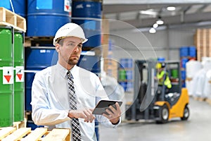 manager in a logistic company work in a warehouse with chemicals - checking goods with tablet