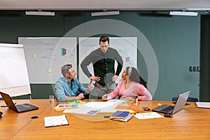 Manager looking at multiracial colleagues discussing strategy in meeting at creative office