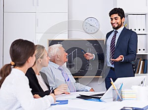 Manager male is reading financial report to colleagues on meeting