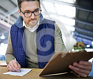 Manager man, glasses and clipboard in logistics warehouse for inspection or inventory checkup. Male supervisor, writing