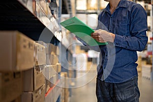 Manager man worker doing stocktaking of product management in cardboard box on shelves in warehouse. Physical inventory count..