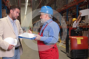 Manager and older worker in warehouse