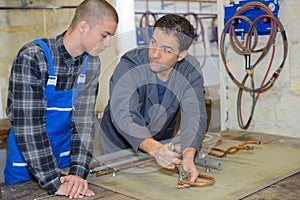 Manager showing trainee how to work with blowtorch