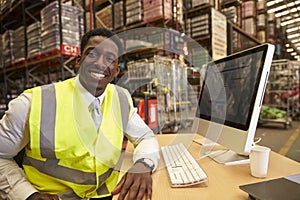 Manager in the on-site office of a warehouse looks to camera