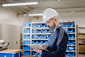 Manager in suit controlling goods in a warehouse.