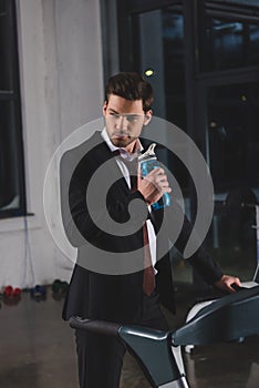 manager in suit training on treadmill with sport bottle