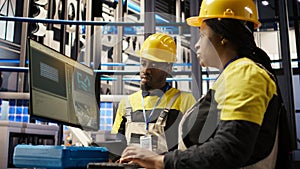Manager supervising technician in factory using PC to diagnose malfunctions photo