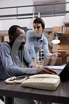 Manager and supervisor looking at cargo stock analyzing transportation logistics on laptop computer