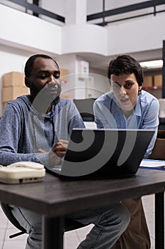 Manager and supervisor looking at transportation logistics on laptop computer searching for online orders